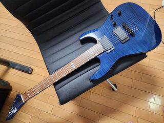 椅子の上にギターを載せて弦の張替えをしている様子
